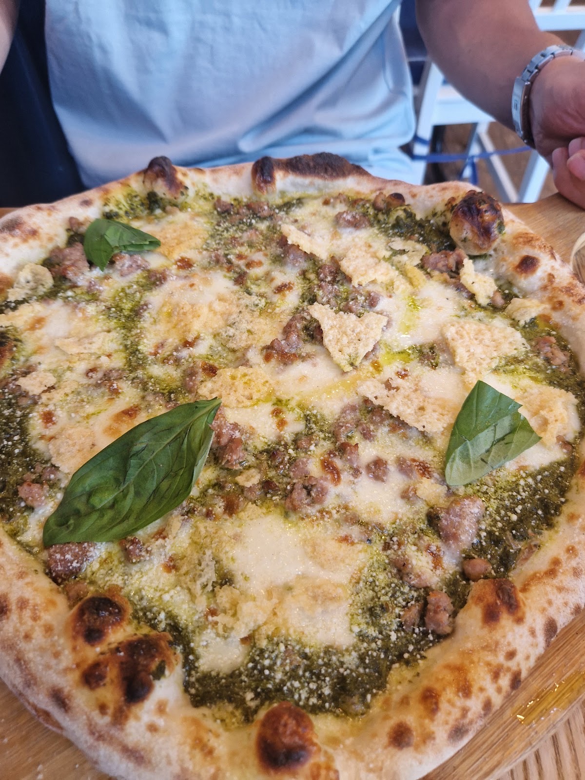 Pesto and mozzarella pizza with basil leaves on a wooden board
