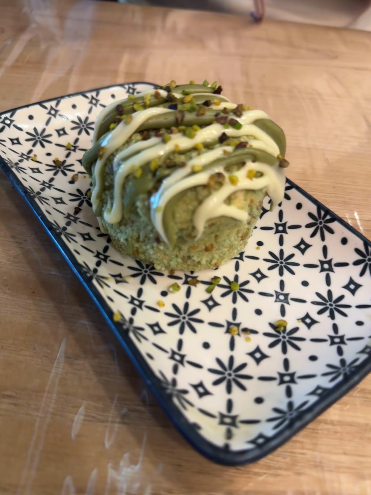 Rolled stuffed dish drizzled with pesto and white sauce on a patterned plate